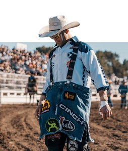 Bullfighter Dusty Tuckness in a white cowboy hat, striped shirt and sponsor shorts.