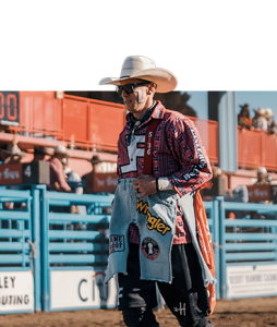 Bullfighter Nathan Harp in a white cowboy hat and red plaid shirt, standing by the chutes.