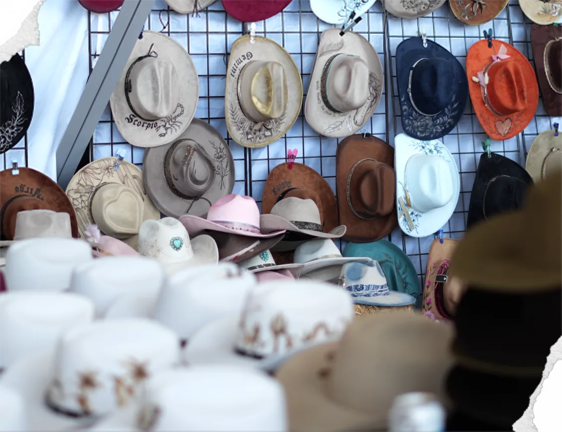Cowboy hats in every colour hang on a vendor’s display wall, with white hats stacked in front.