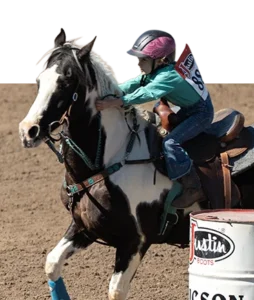 A young Barrel Racing competitor rounding a barrel on a paint horse